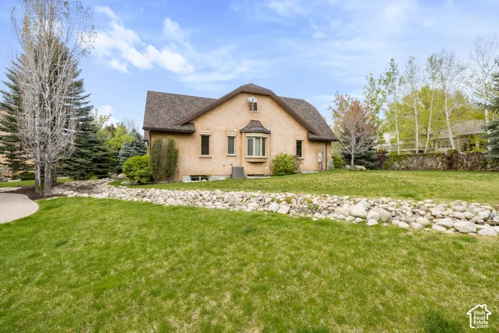 Stucco exterior with a bay window, a pitched roof, and a rock-lined dry creek bed