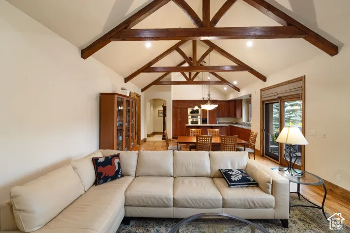 Vaulted ceiling with exposed wood beams, wood-finish flooring, built-in cabinetry, and sliding glass door