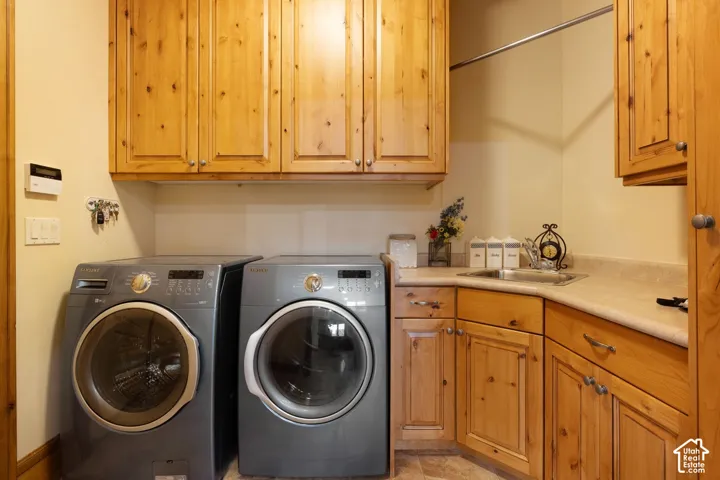 Wood cabinetry with brushed nickel hardware, light-toned countertops, and a utility sink