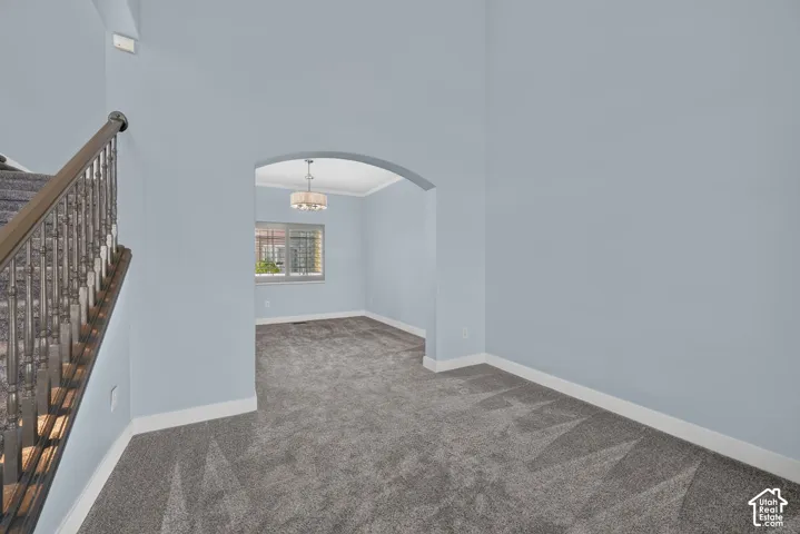 Archway entry leading to a room with a decorative chandelier, window with blinds, and crown molding