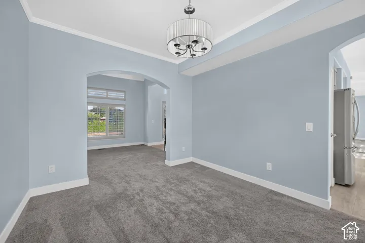 Archway entry, crown molding, modern drum pendant light, white trim, and light blue wall finish