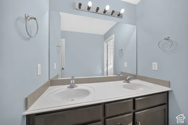 Dual undermount sinks with chrome fixtures, a large vanity mirror, and a multi-bulb vanity light
