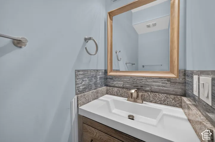 Vanity with integrated rectangular sink, granite countertop, wood-finish cabinetry, and a framed mirror