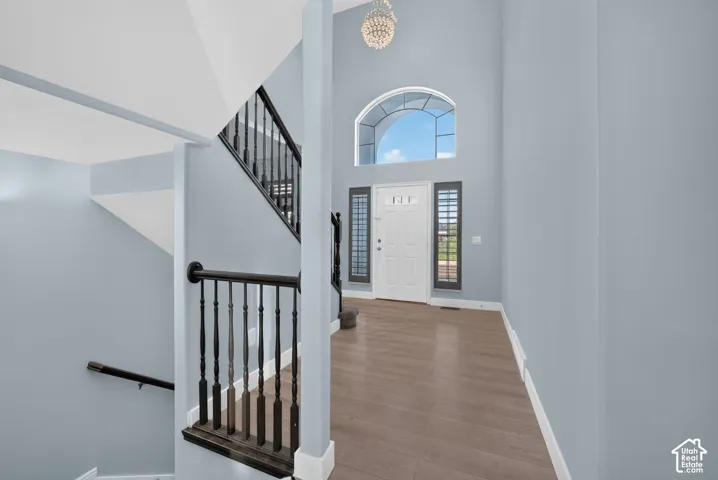 Two-story foyer featuring an arched transom window, a crystal chandelier, and wood-finish flooring