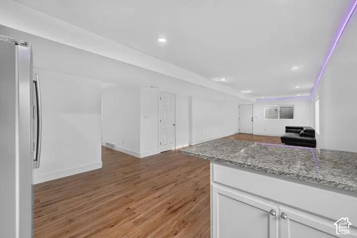 Wood-finish flooring throughout, recessed ceiling lighting, light-colored walls, and a built-in counter with a speckled surface