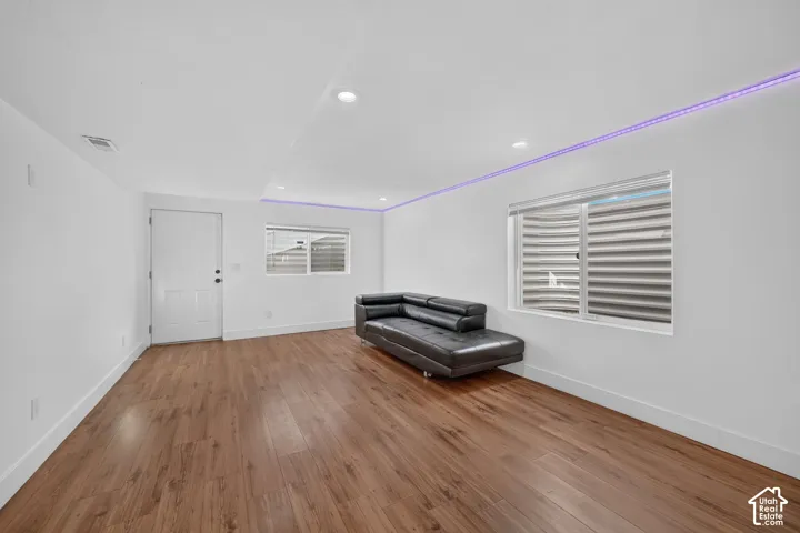 Wood-finish flooring throughout, recessed ceiling lighting, and multiple windows with horizontal blinds
