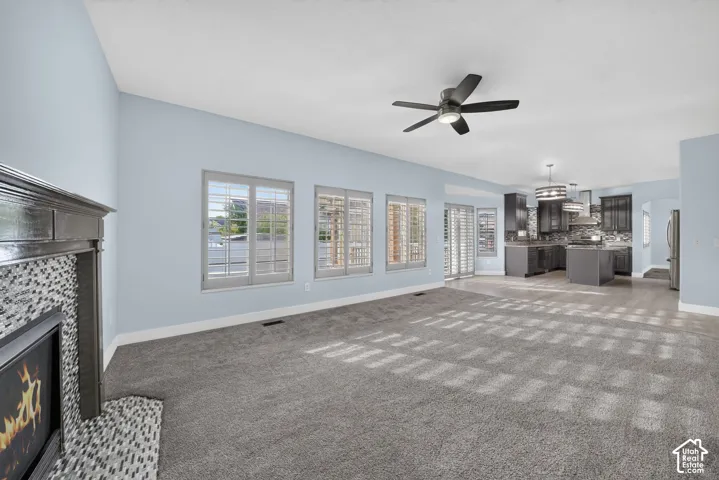 Spacious interior with plush carpeting, a modern ceiling fan, and multiple windows