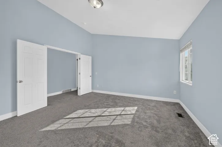 Spacious room with light blue walls, gray carpeting, and a single window with blinds