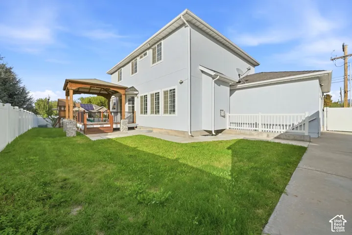 Spacious rear yard with a gazebo-covered deck, privacy fencing, and an expansive lawn area