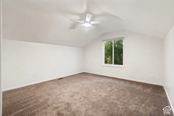 Room featuring vaulted ceilings, a ceiling fan, a window, and wall-to-wall carpeting