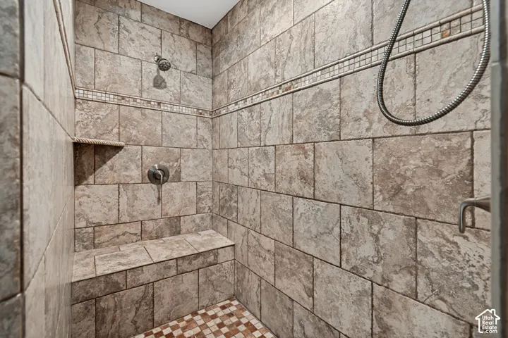 Tiled shower with a built-in bench, recessed shelf, and decorative mosaic accent band