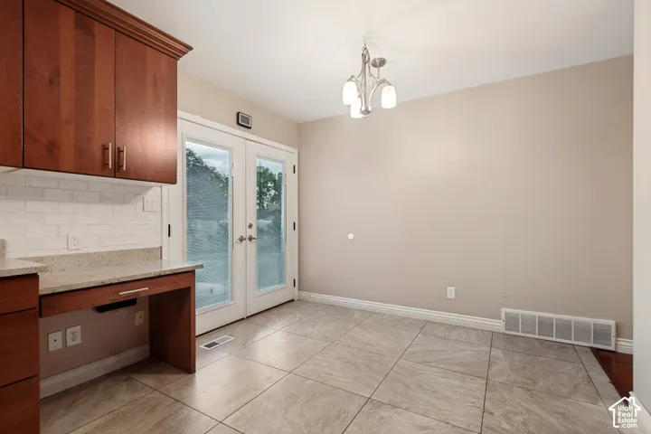 Cherry wood-finish cabinetry, light-toned countertop, white subway tile backsplash, and tile flooring