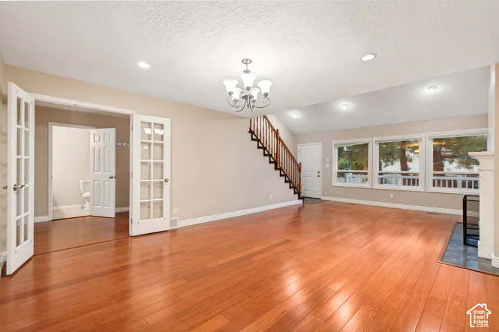 Expansive living area with wood-finish flooring, vaulted ceilings, and recessed lighting