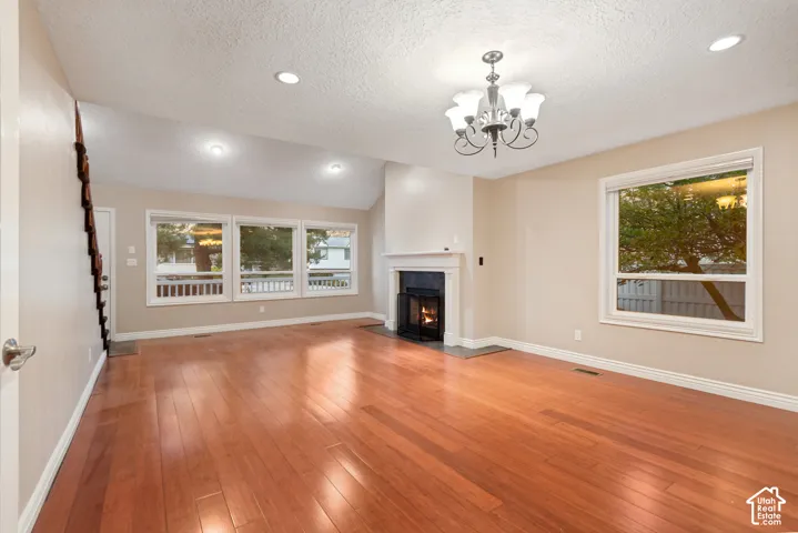 Hardwood flooring, vaulted ceiling, recessed lighting, gas fireplace with mantel, and a multi-pane window
