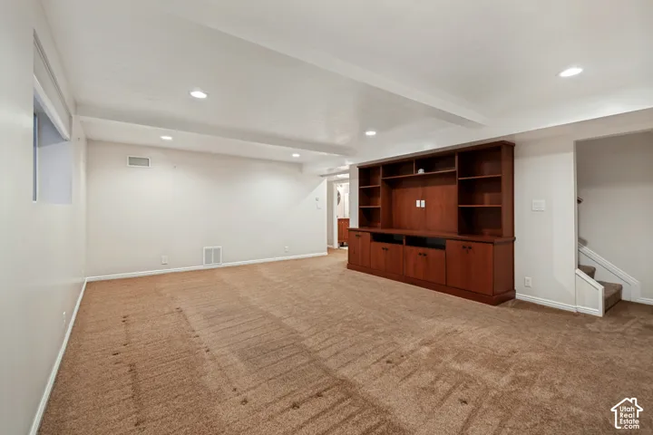 Spacious room with recessed lighting, built-in shelving, integrated cabinetry, and carpeted flooring