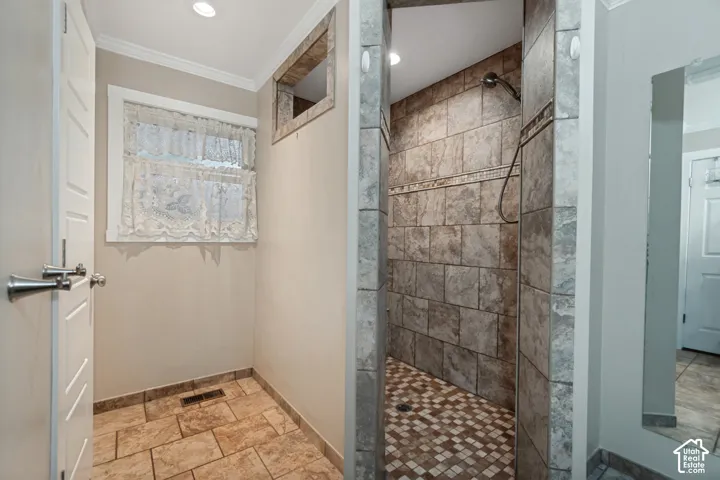 Tile-surrounded shower with a mosaic tile floor, an accent tile border, and a handheld showerhead