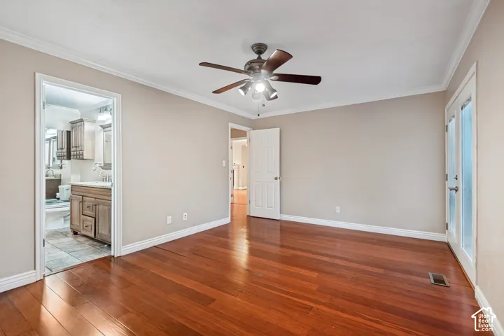 Hardwood flooring, ceiling fan with integrated lighting, crown molding, white trim, and a white door with frosted glass panels