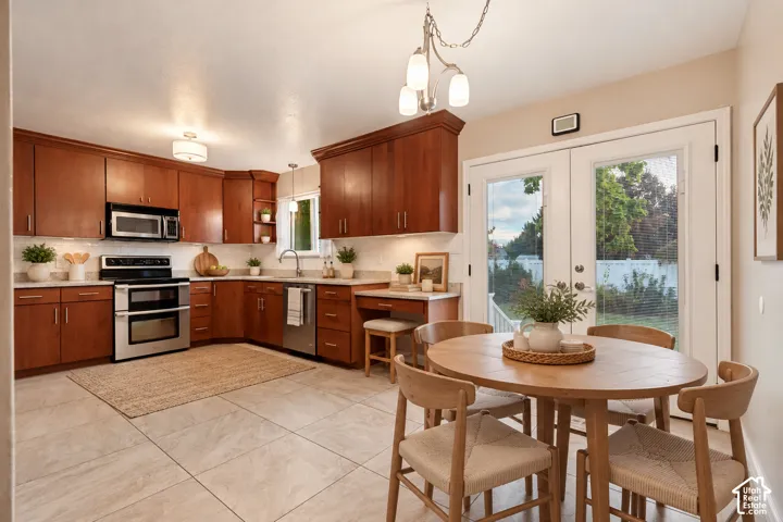 This is an AI furnished room Kitchen featuring stained wood cabinetry, stone-finish tile flooring, built-in stainless steel appliances, a desk area, and double glass doors