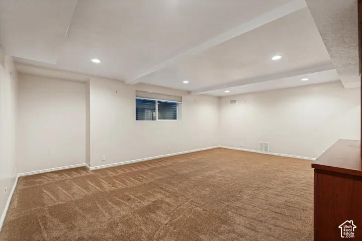 Spacious room featuring neutral carpeting, recessed lighting, and a single window with blinds