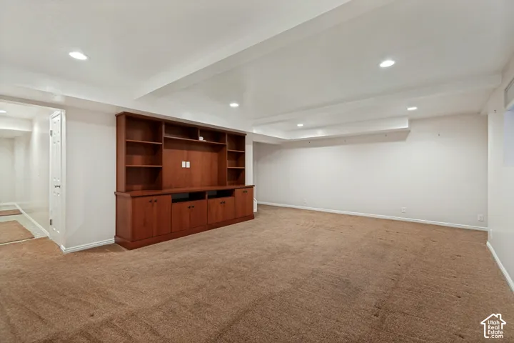 Spacious room featuring a built-in media cabinet, recessed lighting, and soft carpeting