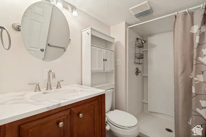 Vanity with a white countertop and undermount sink, brushed nickel faucet, large round mirror, white built-in shelving, and a shower stall