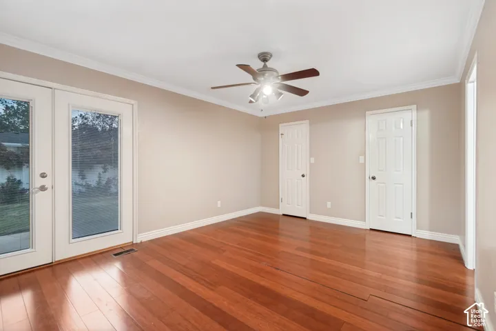 Hardwood flooring, crown molding, ceiling fan with integrated lighting, and white paneled doors