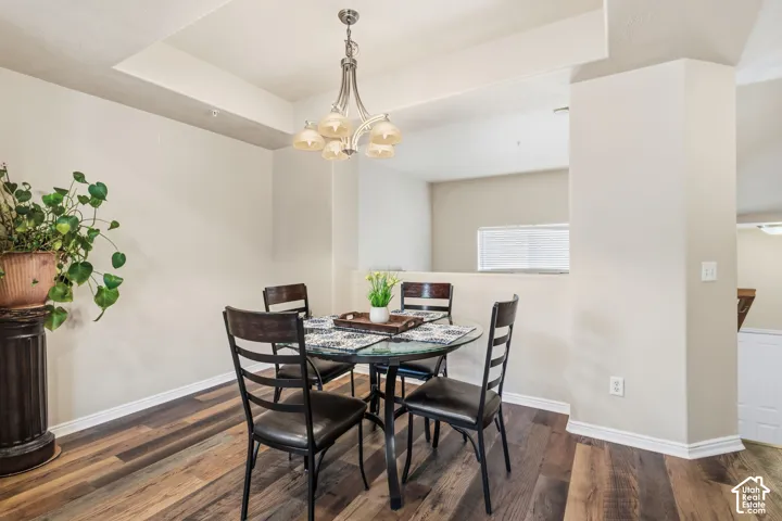 Wood-finish flooring, recessed ceiling detail, and a built-in chandelier