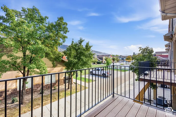 Exterior balcony with composite decking and black metal railings with view of swimming pool