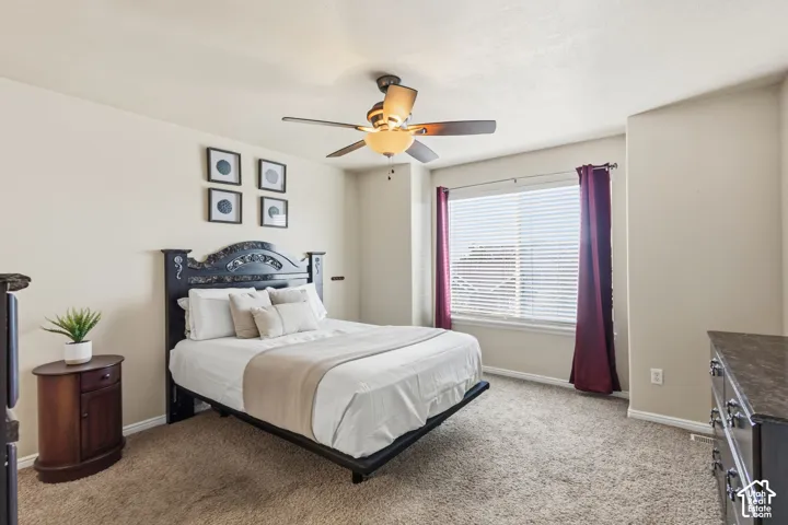 Primary suite with a large window with blinds, and a ceiling fan with integrated lighting