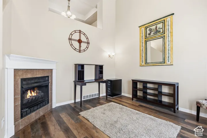 Gas fireplace with a tile surround and white mantel, wood-finish flooring, and high ceilings with upper-level openings