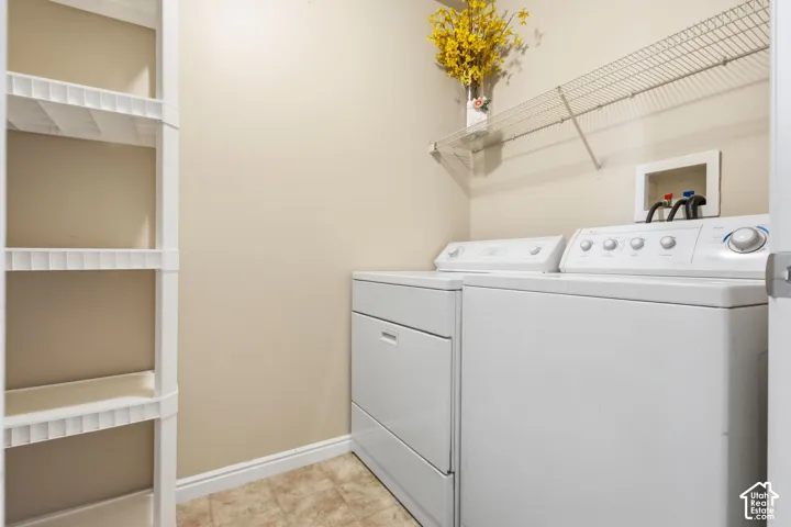 Laundry area featuring a washer and dryer, shelving, and tiled flooring