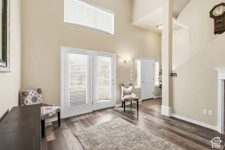 Main floor living room with high ceilings, wood-finish flooring, and white double doors to outdoor patio