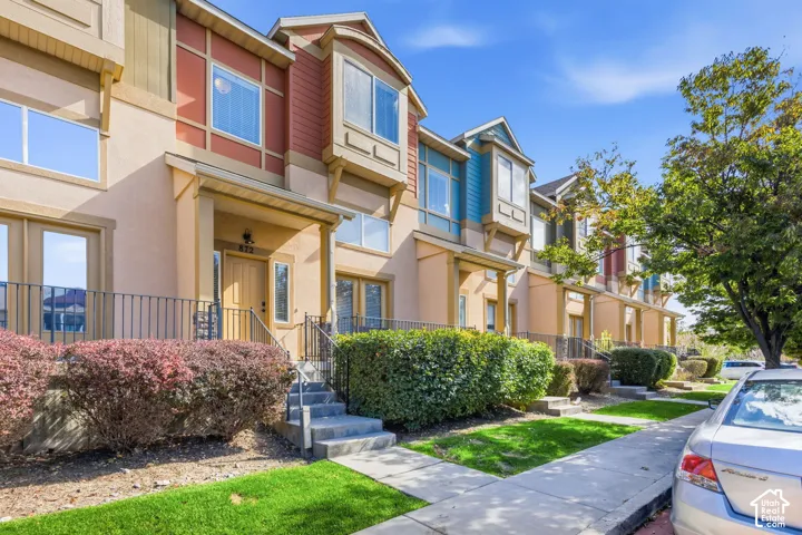 Townhome exterior with a distinctive multi-color facade, bay windows, covered entry, and mature landscaping