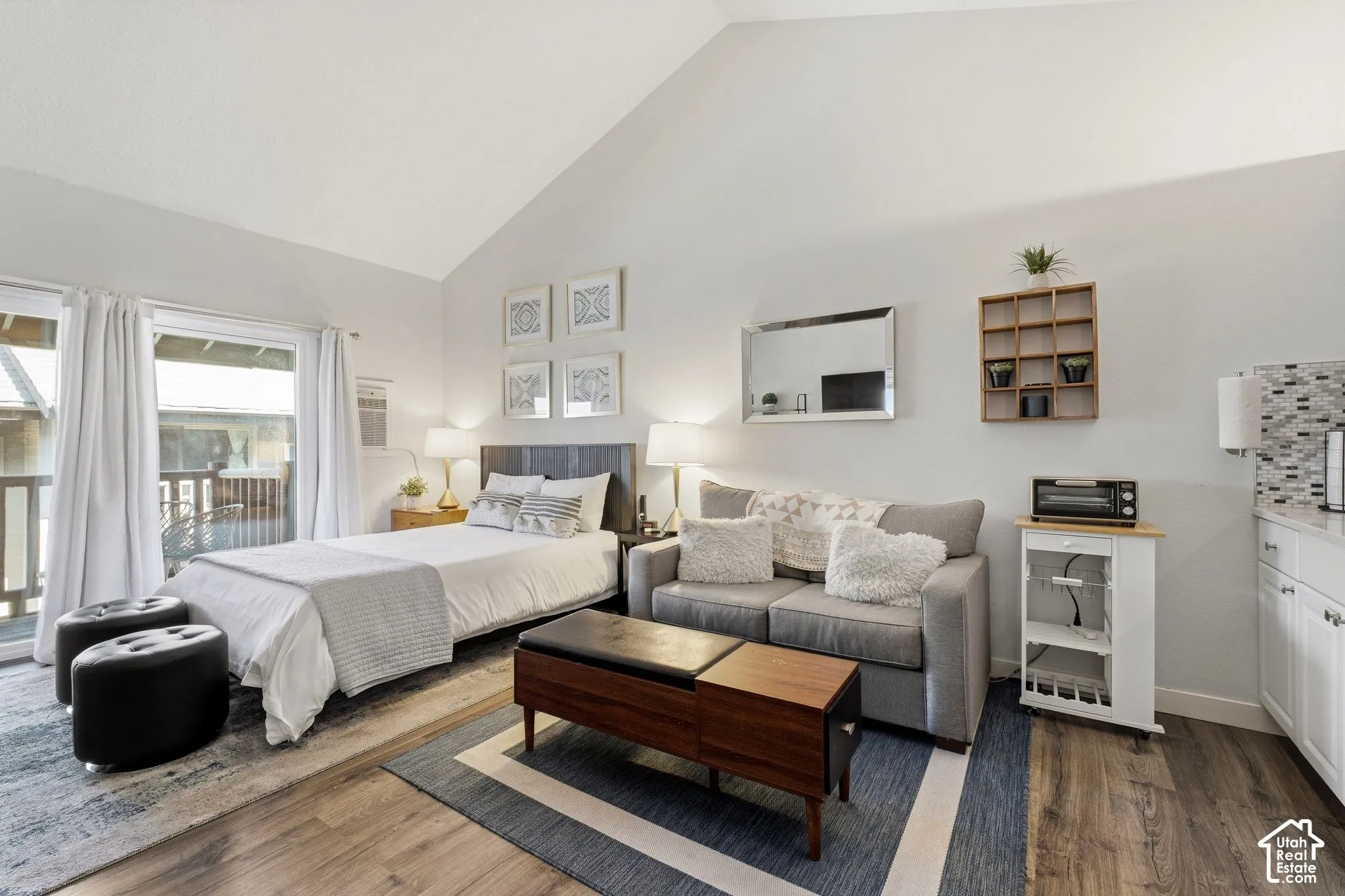 Vaulted ceiling, wood-finish flooring, sliding glass door, mosaic tile backsplash, and built-in cabinetry