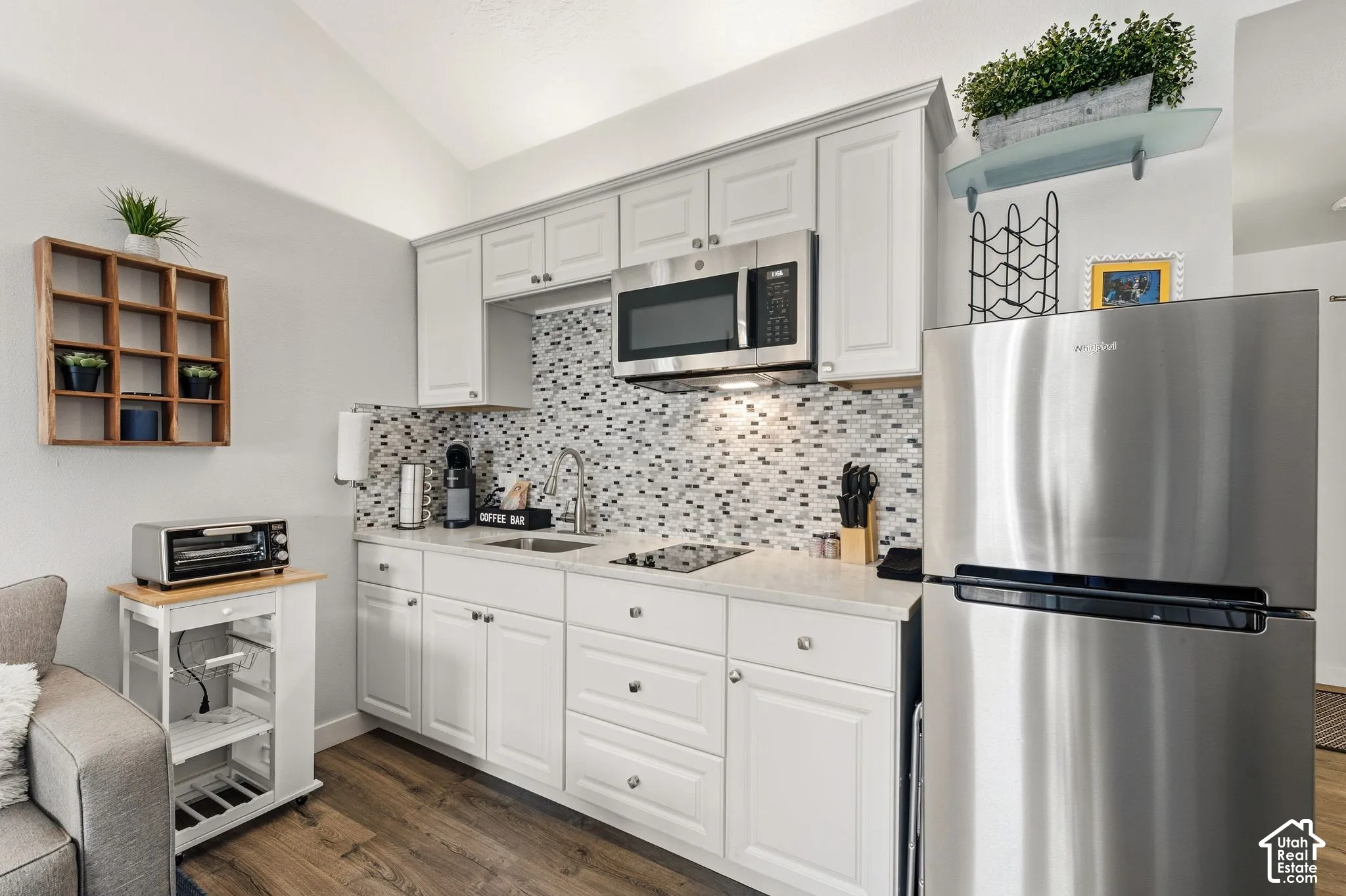 Kitchenette featuring white cabinetry, a mosaic tile backsplash, stainless steel appliances, and wood-finish flooring