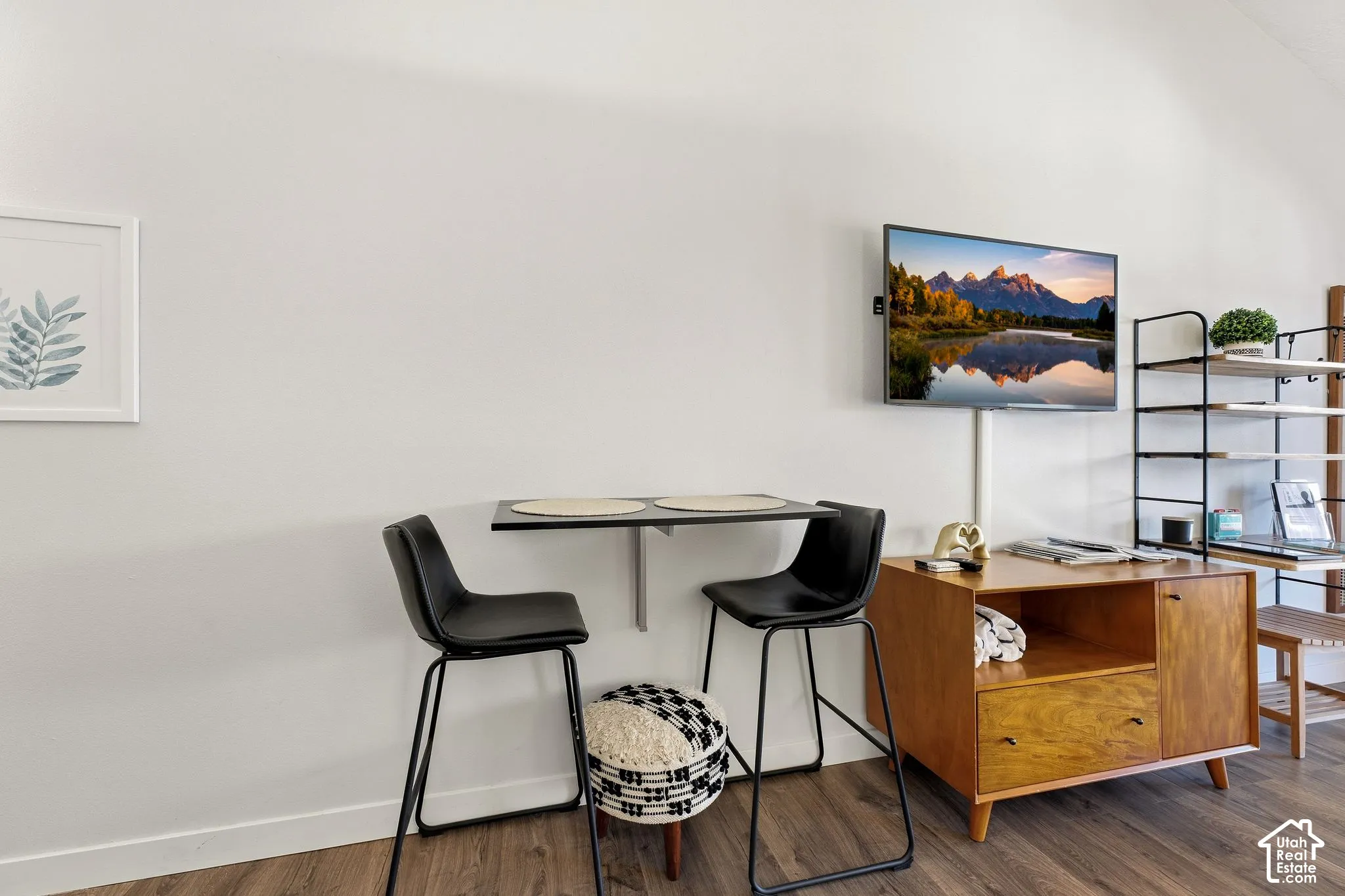 Wall-mounted television with a fixed folding table, wood-finish flooring, and a built-in wooden media console