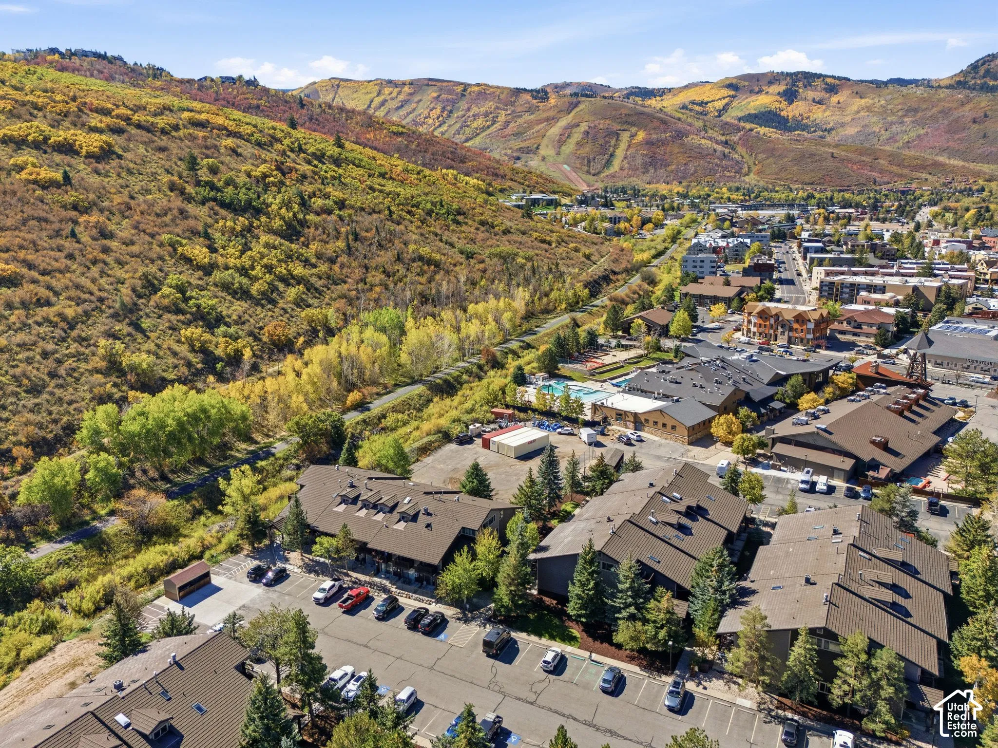 Mountainous terrain, extensive tree coverage, asphalt parking areas, multiple residential structures, and a swimming pool facility