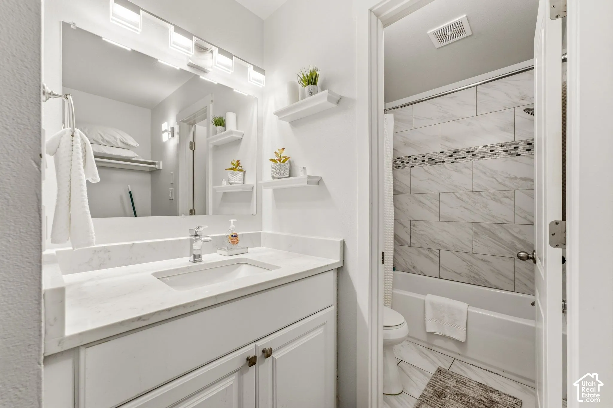 White vanity with a single basin sink, chrome faucet, and integrated countertop