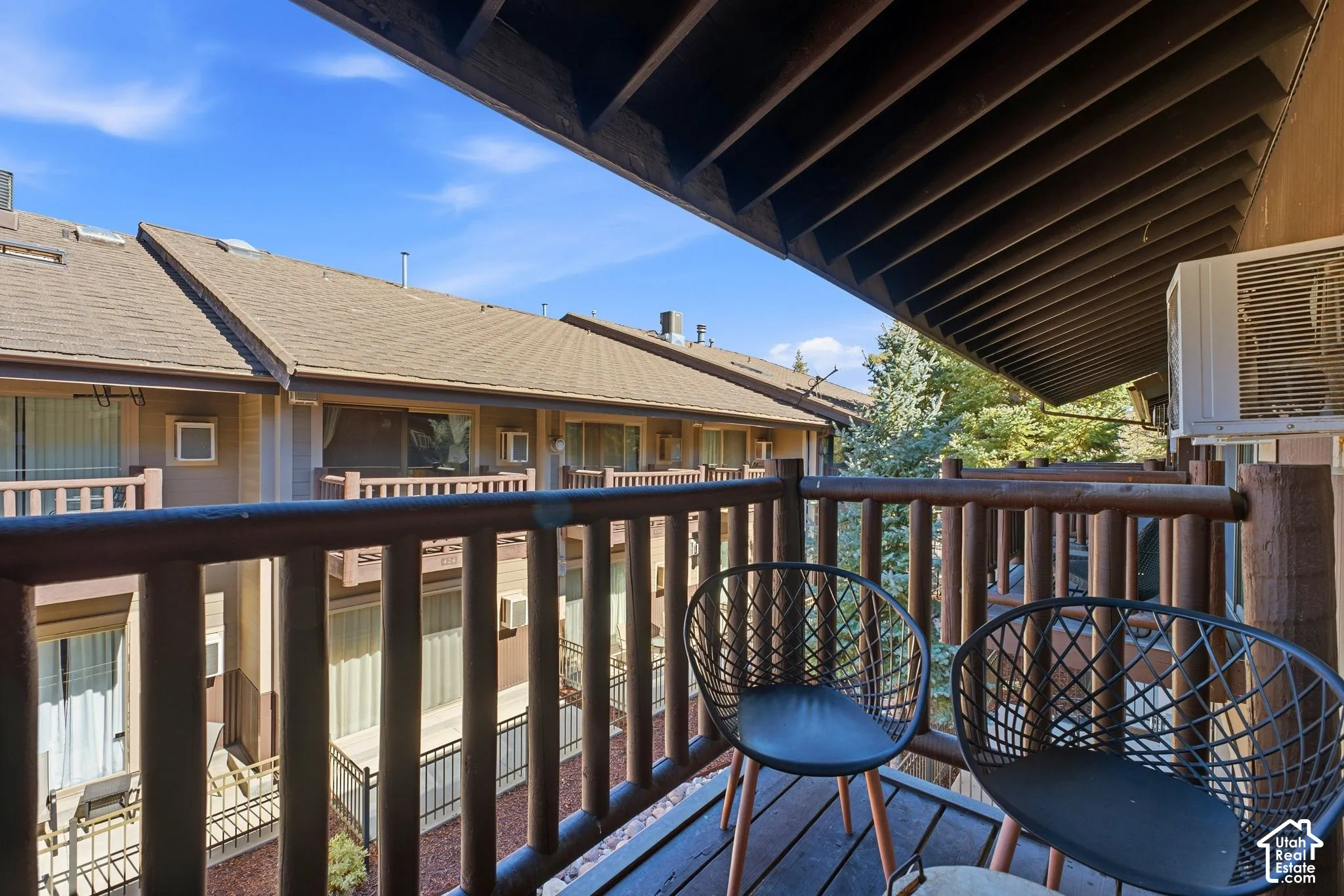 Private balcony with wood-finish railing, exposed wood-beam ceiling, and wood-plank flooring