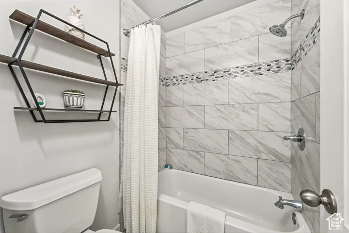 Bathtub with subway tile surround, mosaic accent strip, and a chrome showerhead