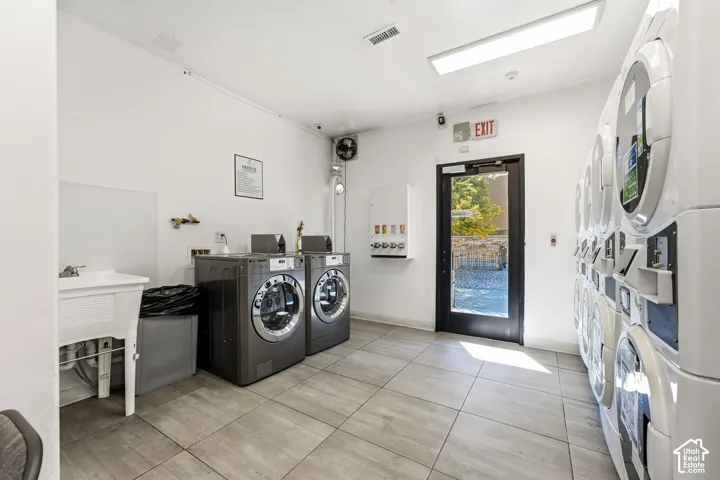 Utility room with tile flooring, a utility sink, and multiple washing machines