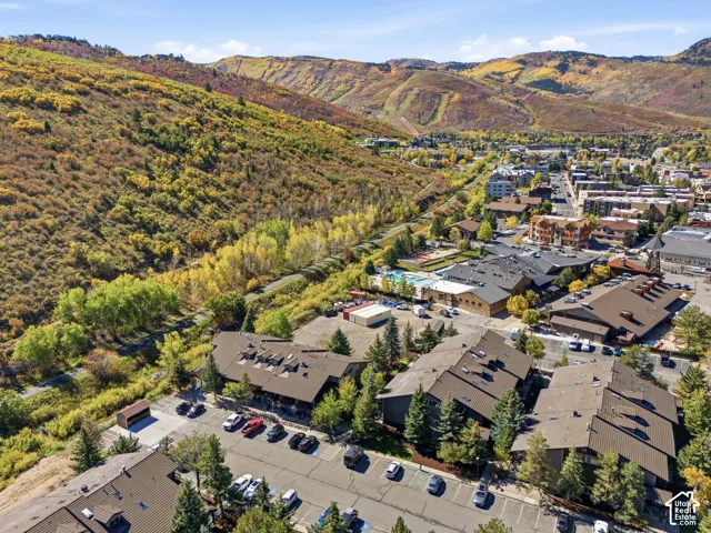 Mountainous terrain, extensive tree coverage, asphalt parking areas, multiple residential structures, and a swimming pool facility