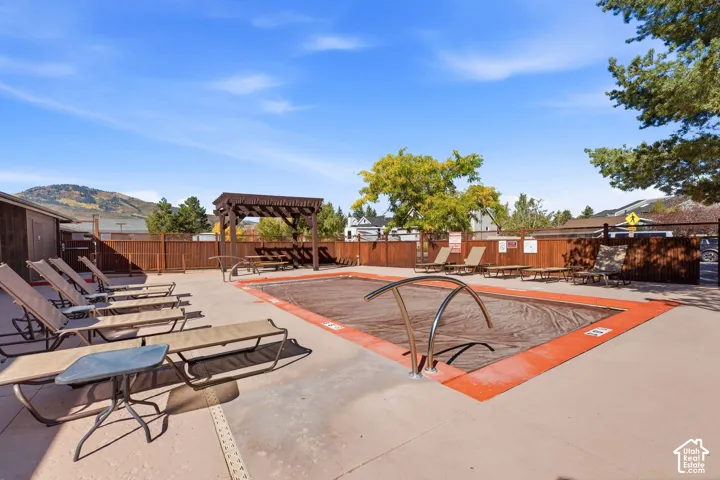 Outdoor pool area featuring a concrete deck and a wooden pergola