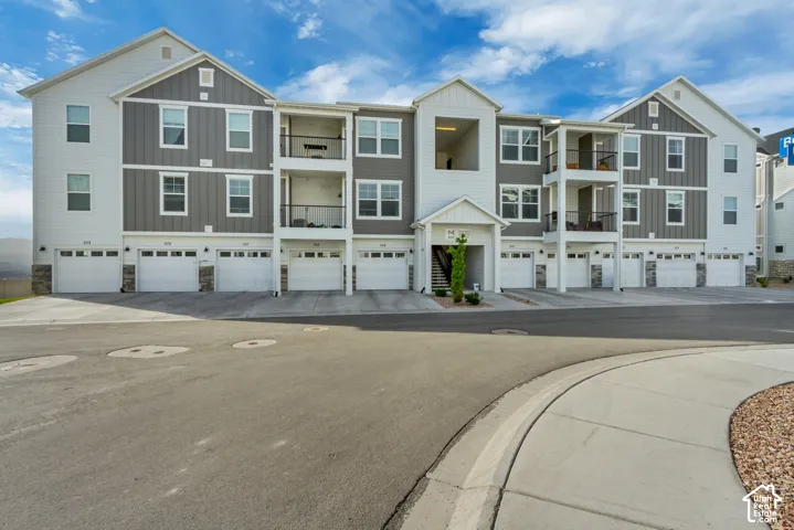 Multi-story residential building with attached garages, individual balconies, and stone veneer accents