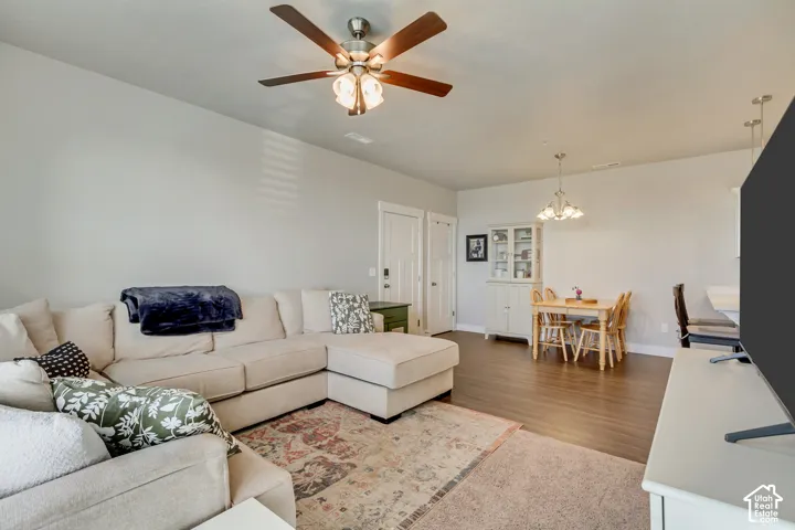 Open-concept living space featuring wood-finish flooring, a ceiling fan with integrated lighting, and recessed lighting fixtures