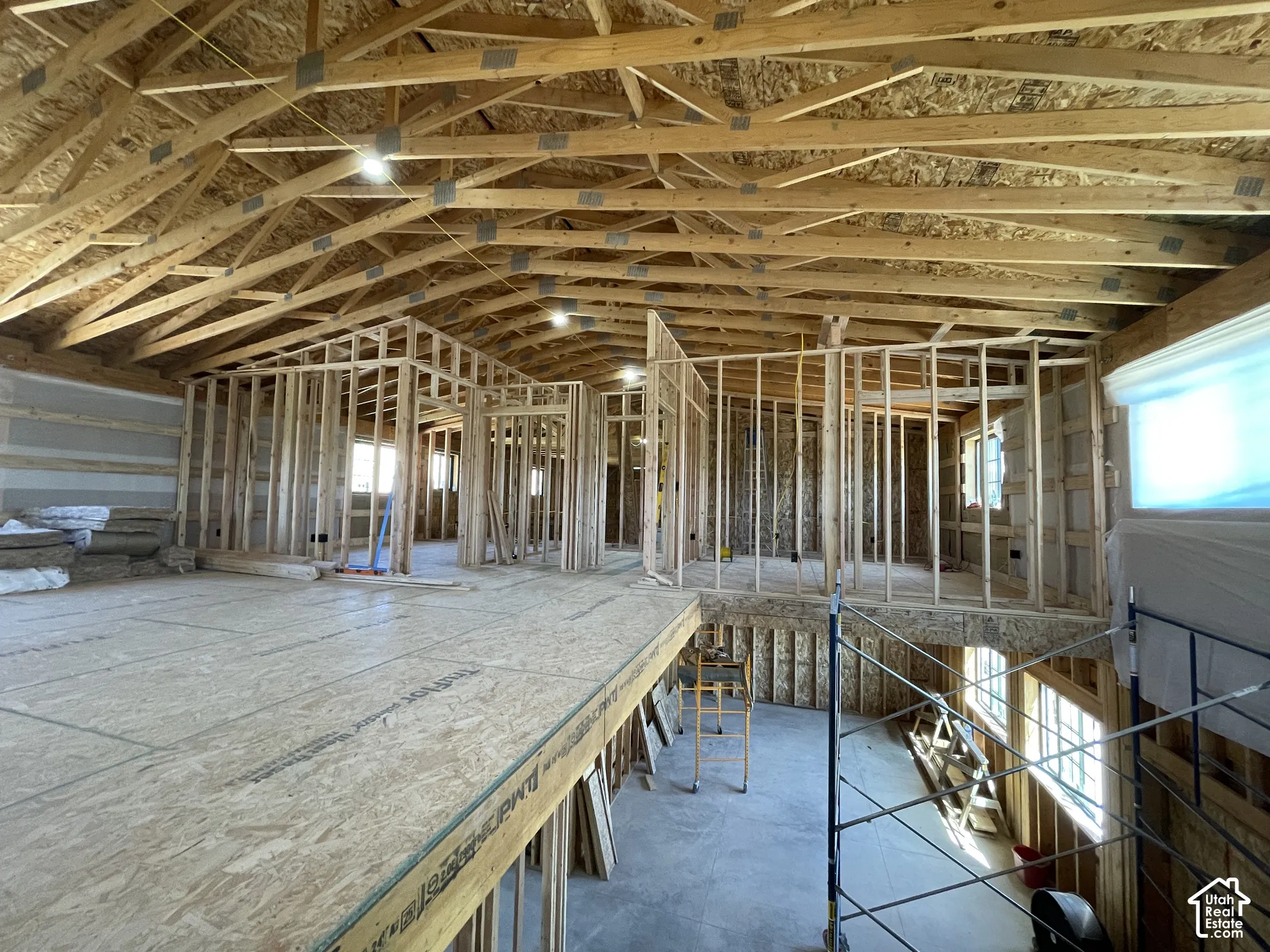 Open concept framing with exposed wood trusses, recessed lighting, and ample natural light