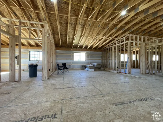 Open-concept interior with vaulted ceilings, exposed wood framing, and multiple windows providing natural light