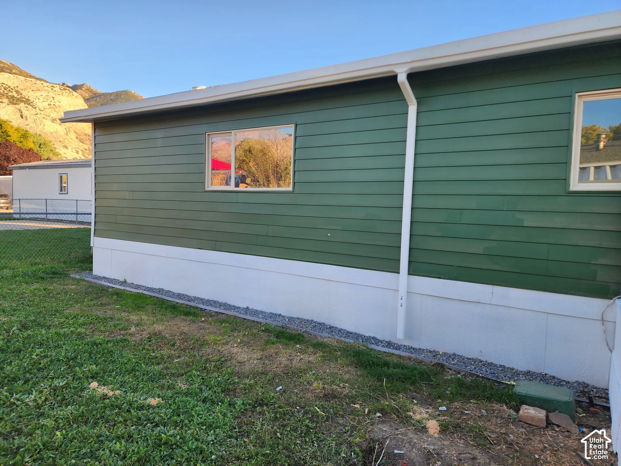 Green horizontal siding with white trim and a white foundation