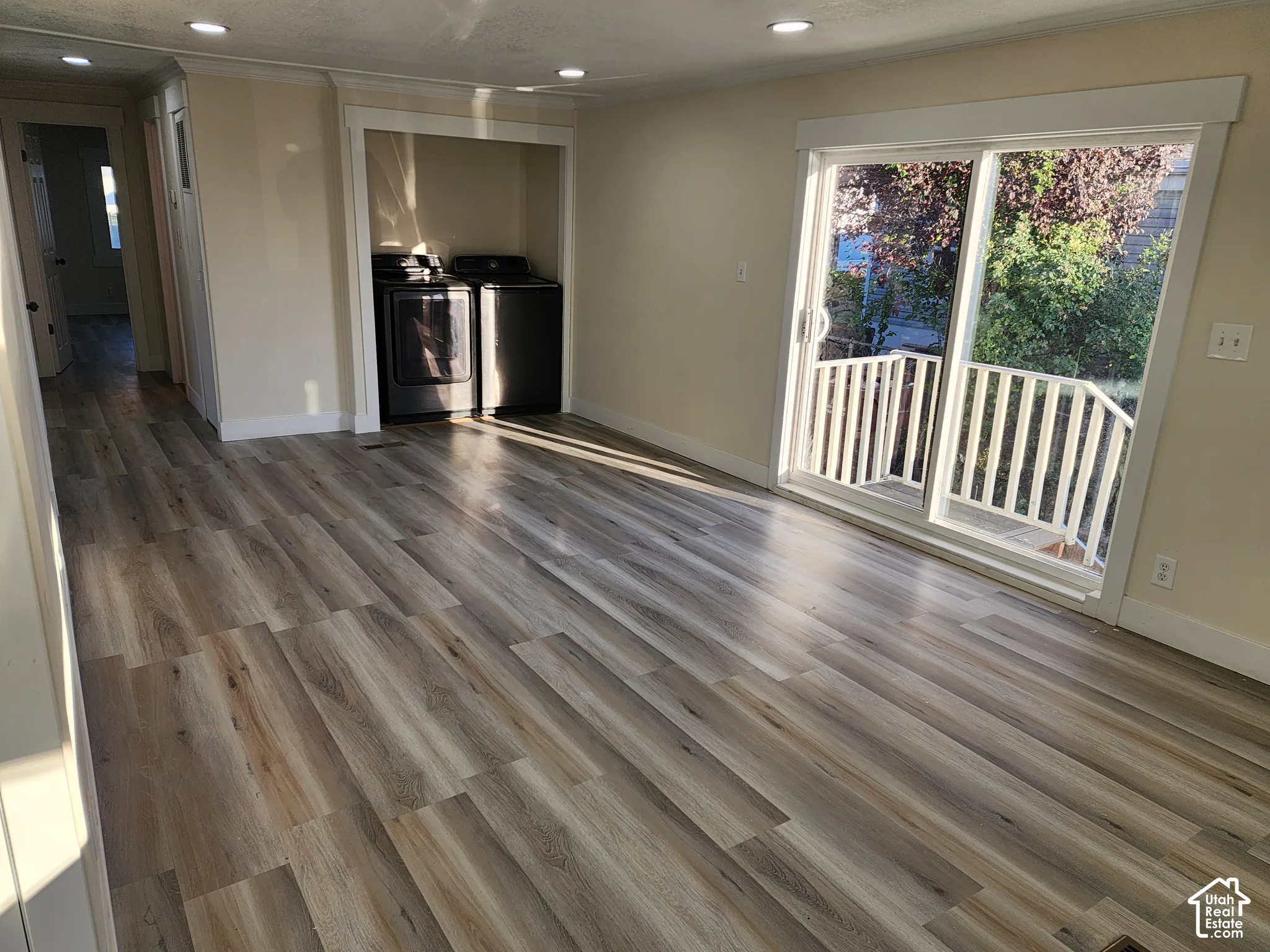 Wood-finish flooring throughout, recessed ceiling lighting, sliding glass door with balcony access, and an integrated laundry area