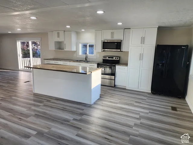 Contemporary kitchen featuring white cabinetry, light-toned wood-finish flooring, and recessed lighting